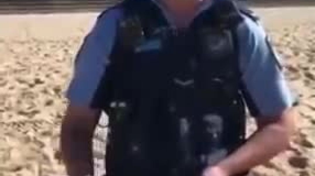 Australian Police approach a man, asking for Identification Papers, for sunbathing on the beach.