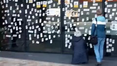 Stickers of the dead caused by the jabs are posted on windows of the BBC...