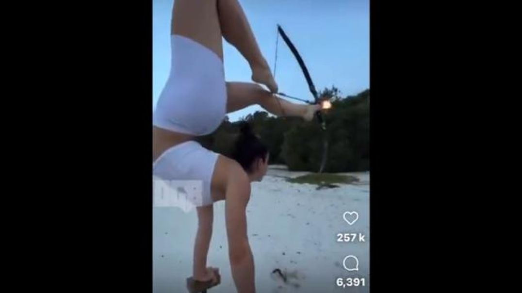 Cute Girl in a handstand shoots fire ? arrow with feet